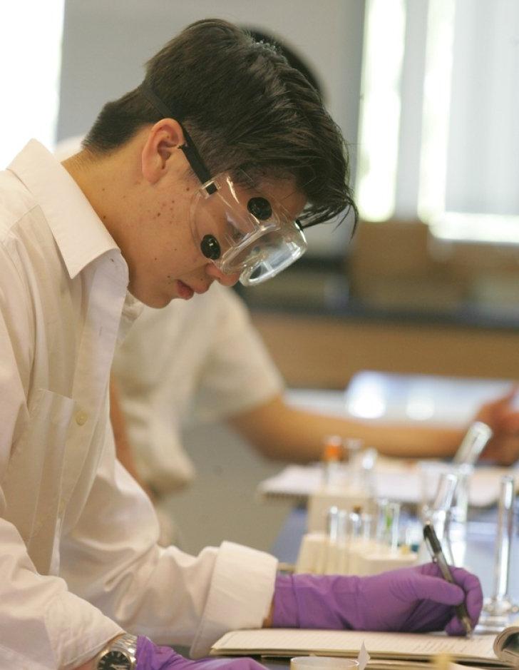 A student writes notes in a lab run by Pitzer's Department of Natural Sciences